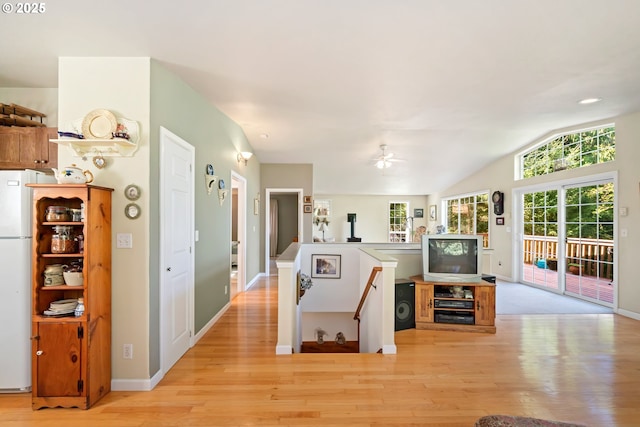 interior space with a ceiling fan, light wood-type flooring, freestanding refrigerator, open floor plan, and lofted ceiling
