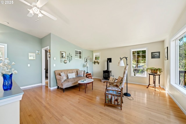 living room featuring vaulted ceiling, a healthy amount of sunlight, a wood stove, and light wood-type flooring