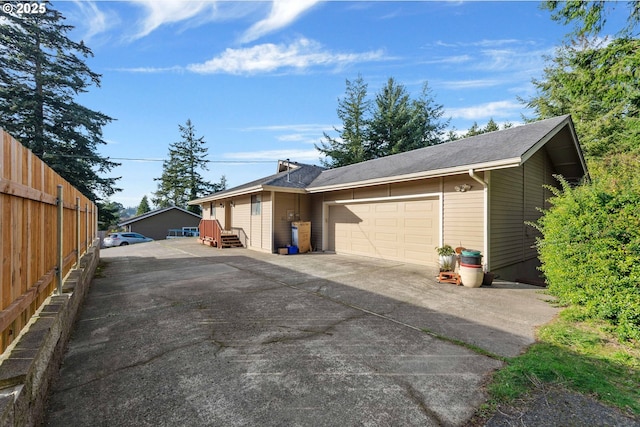 view of property exterior featuring concrete driveway, fence, and an attached garage