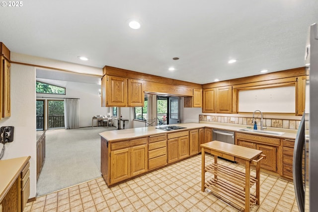 kitchen with stainless steel appliances, light countertops, light carpet, a sink, and a peninsula