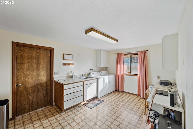 kitchen featuring light countertops, white cabinetry, a sink, a textured ceiling, and independent washer and dryer