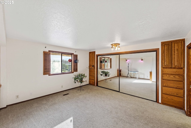 unfurnished room with visible vents, baseboards, a textured ceiling, and light colored carpet