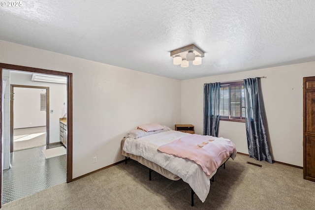 bedroom featuring light carpet, baseboards, visible vents, ensuite bathroom, and a textured ceiling