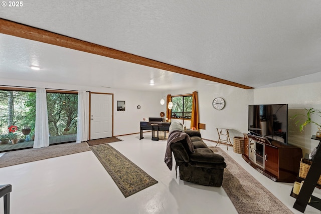 living area with a textured ceiling, beamed ceiling, and finished concrete floors