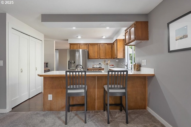 11595 SW Fairview Ln, Tigard, OR 97223 - kitchen with stainless steel appliances, brown cabinetry, a peninsula, light countertops, and dark carpet