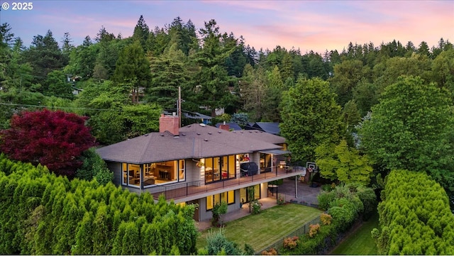 3132 SW Altadena Ter, Portland, OR 97239 - back of house at dusk with a lawn, a chimney, and a deck