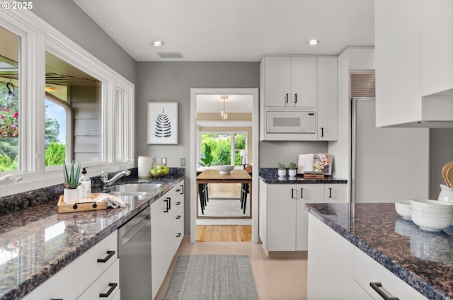 3132 SW Altadena Ter, Portland, OR 97239 - kitchen featuring white microwave, a sink, stainless steel dishwasher, white cabinets, and dark stone counters