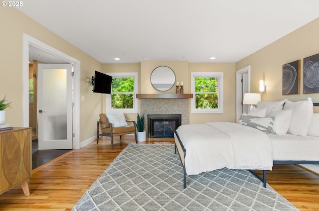 3132 SW Altadena Ter, Portland, OR 97239 - bedroom with wood finished floors, multiple windows, baseboards, a glass covered fireplace, and recessed lighting
