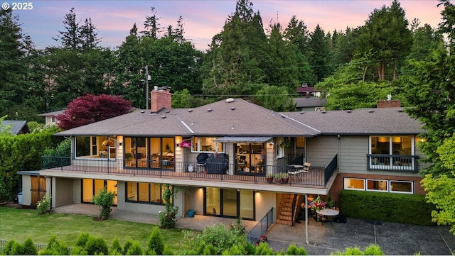 3132 SW Altadena Ter, Portland, OR 97239 - back of property at dusk with a chimney, a patio area, and a yard