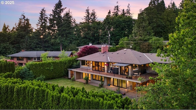 3132 SW Altadena Ter, Portland, OR 97239 - back of property at dusk featuring a chimney and a patio