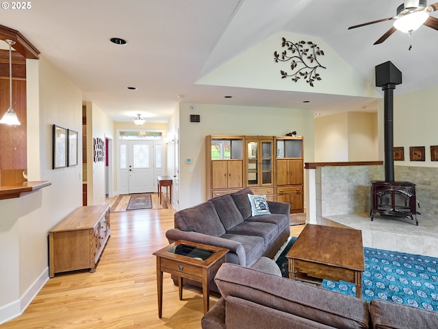 living room featuring light hardwood / wood-style flooring, a wood stove, and ceiling fan