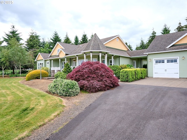 view of front of home featuring a porch, a garage, and a front lawn