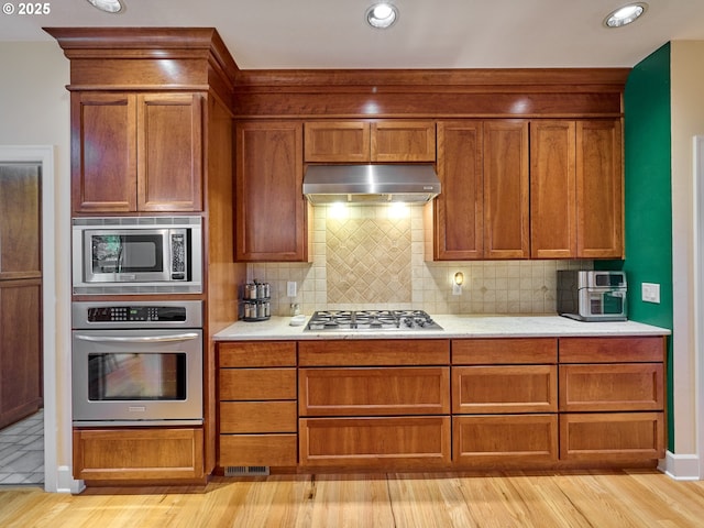 kitchen featuring decorative backsplash, light hardwood / wood-style flooring, and stainless steel appliances