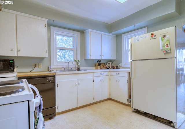 kitchen featuring a sink, white appliances, white cabinetry, and light countertops