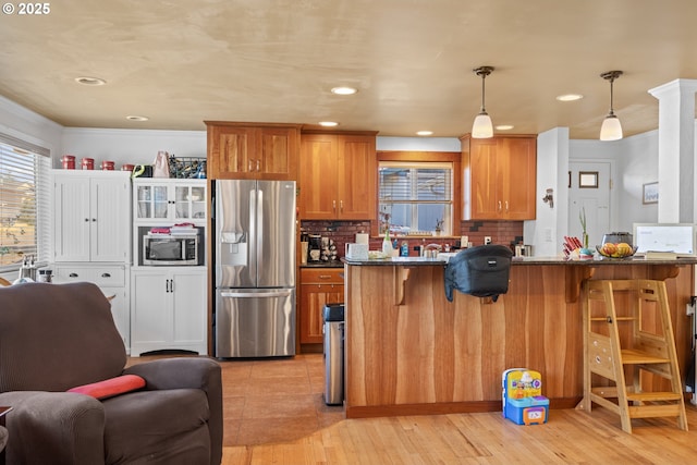 1910 Lincoln St, North Bend, OR 97459 - kitchen featuring appliances with stainless steel finishes, a kitchen bar, brown cabinets, tasteful backsplash, and open floor plan