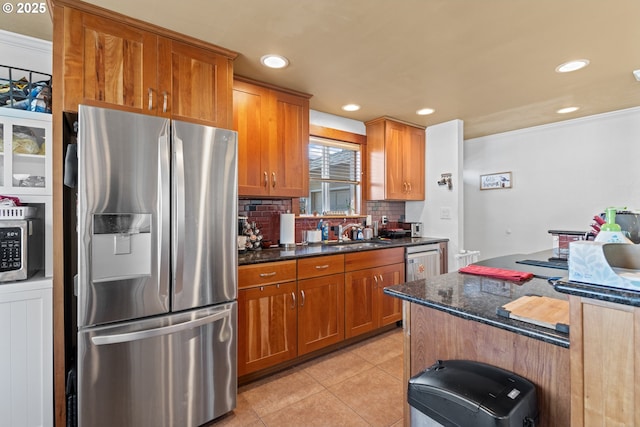 1910 Lincoln St, North Bend, OR 97459 - kitchen featuring appliances with stainless steel finishes, tasteful backsplash, brown cabinets, light tile patterned floors, and dark stone countertops