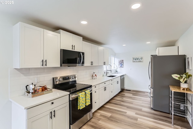 kitchen featuring appliances with stainless steel finishes, decorative backsplash, white cabinets, and sink