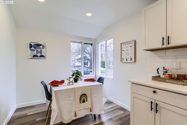 dining area featuring vaulted ceiling and dark hardwood / wood-style flooring