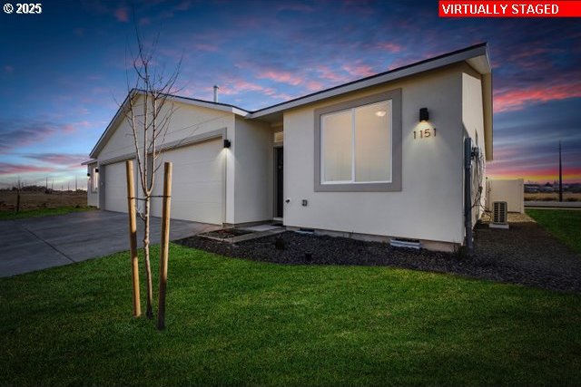 1203 NE Emerald Dr, Hermiston, OR 97838 - ranch-style house with an attached garage, driveway, a lawn, and stucco siding