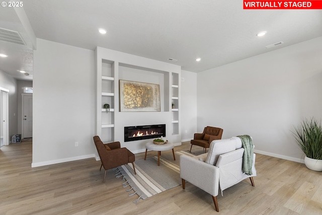 1203 NE Emerald Dr, Hermiston, OR 97838 - sitting room featuring wood finished floors, a glass covered fireplace, built in features, and recessed lighting