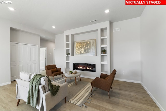 1203 NE Emerald Dr, Hermiston, OR 97838 - sitting room featuring wood finished floors, a glass covered fireplace, built in shelves, and recessed lighting
