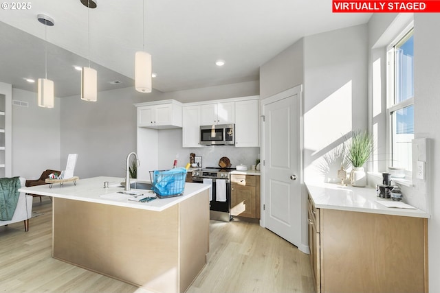 1203 NE Emerald Dr, Hermiston, OR 97838 - kitchen featuring stainless steel appliances, light wood-style flooring, light countertops, white cabinets, and hanging light fixtures