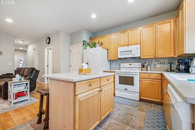 kitchen featuring a center island, light countertops, open floor plan, light brown cabinets, and white appliances