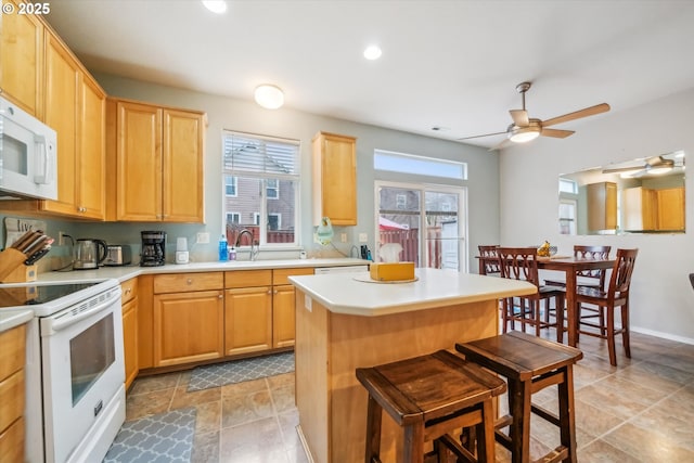 kitchen with light countertops, white appliances, a kitchen bar, and a kitchen island