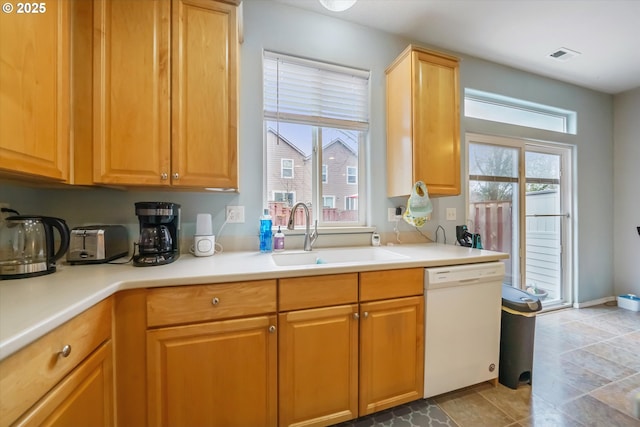 kitchen featuring white dishwasher, visible vents, light countertops, and a sink