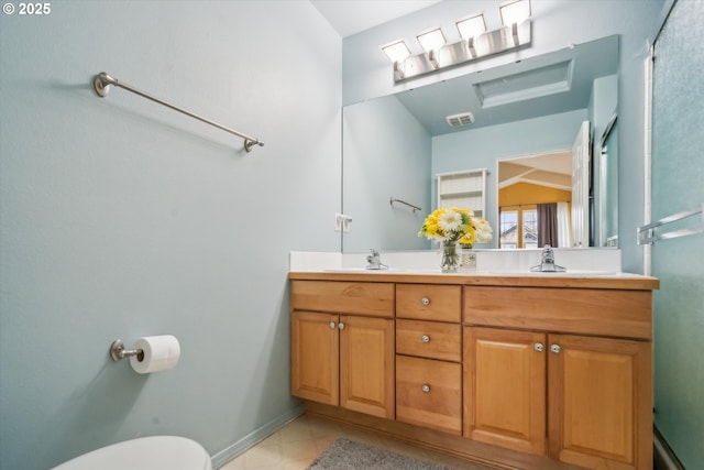 bathroom featuring double vanity, visible vents, toilet, a sink, and baseboards