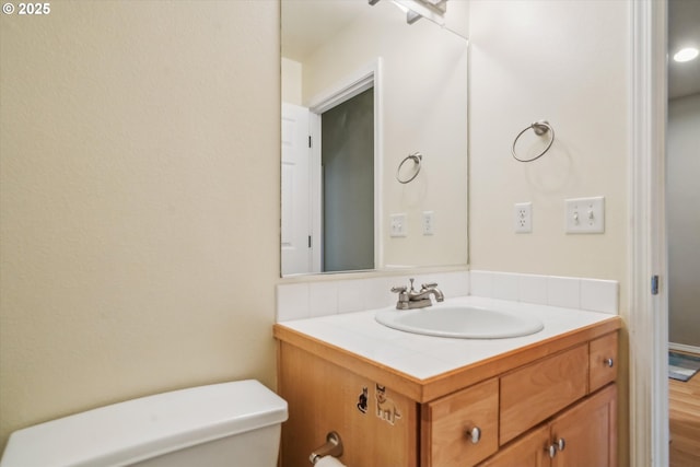 bathroom with wood finished floors, vanity, and toilet