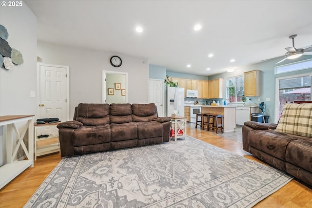 living area with light wood finished floors, a ceiling fan, and recessed lighting