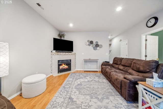 living area with wood finished floors, a tile fireplace, visible vents, and recessed lighting