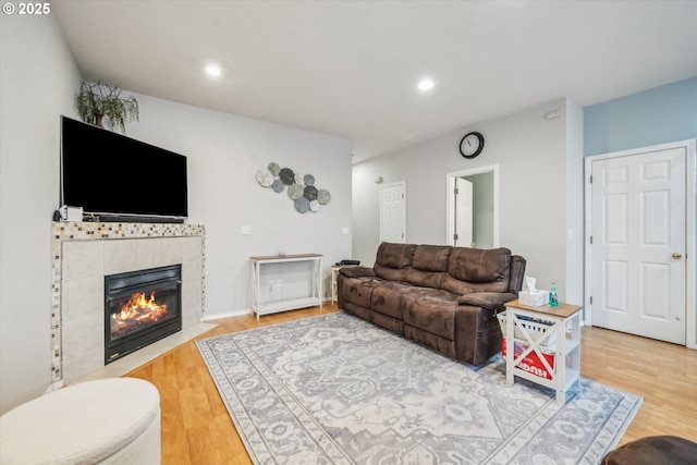 living area featuring recessed lighting, a tiled fireplace, and wood finished floors