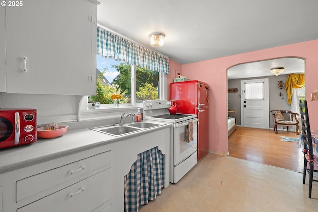 4315 SE Rhodesa St, Milwaukie, OR 97222 - kitchen with white electric range oven, arched walkways, light countertops, light flooring, and freestanding refrigerator