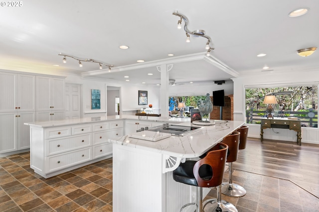 9202 Phey Ln, Florence, OR 97439 - kitchen with light stone countertops, a spacious island, ornamental molding, recessed lighting, and white cabinetry