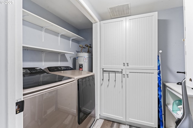 9202 Phey Ln, Florence, OR 97439 - washroom with visible vents, washer and dryer, light wood-style floors, cabinet space, and strapped water heater