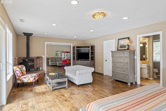 9202 Phey Ln, Florence, OR 97439 - bedroom featuring recessed lighting, a wood stove, ensuite bath, and wood finished floors
