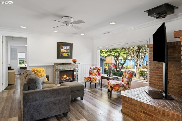 9202 Phey Ln, Florence, OR 97439 - living room with a ceiling fan, a warm lit fireplace, visible vents, and wainscoting