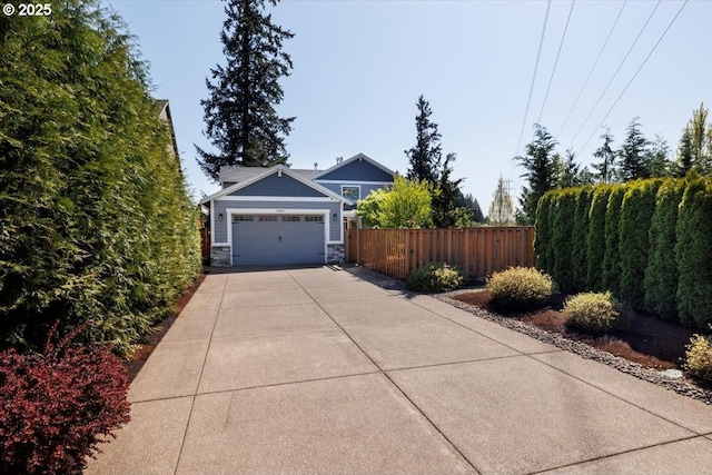 exterior space with fence, stone siding, concrete driveway, and a garage