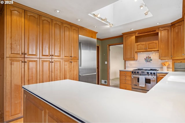 1228 11th St, Astoria, OR 97103 - kitchen featuring high end appliances, light countertops, recessed lighting, tasteful backsplash, and brown cabinets