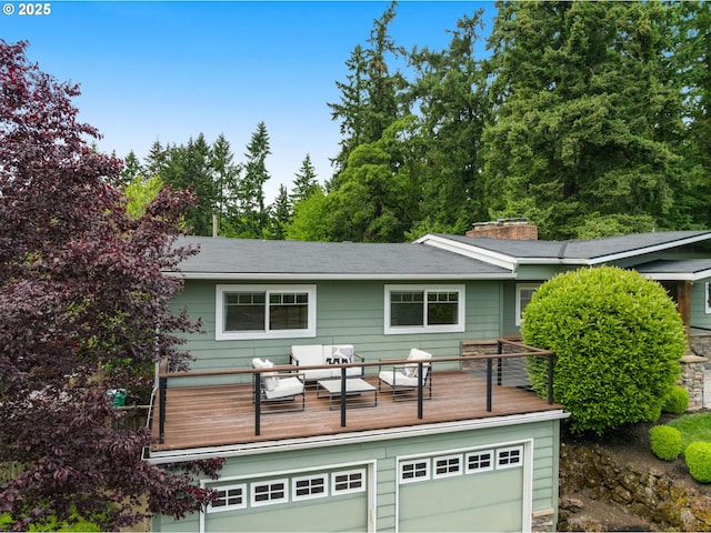 view of front facade featuring a chimney, a deck, an outdoor living space, and an attached garage