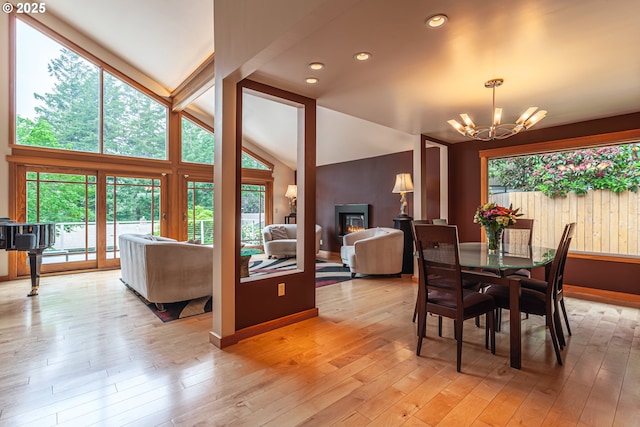 11 Da Vinci St, Lake Oswego, OR 97035 - dining area with a chandelier, lofted ceiling, light wood-style floors, baseboards, and a glass covered fireplace