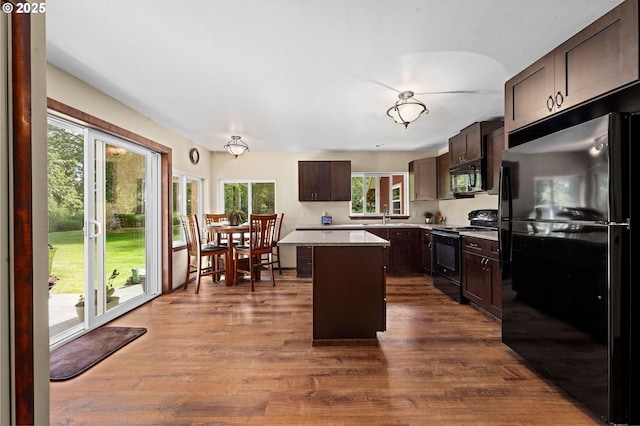 290 12th Ave, Hammond, OR 97121 - kitchen featuring black appliances, dark brown cabinets, a center island, light countertops, and dark wood-style floors