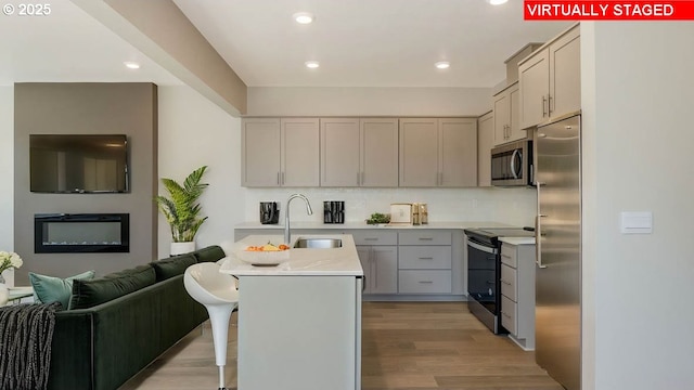 17197 SE Maple Hill Ln, Happy Valley, OR 97086 - kitchen with stainless steel appliances, light wood-type flooring, light countertops, tasteful backsplash, and a kitchen breakfast bar
