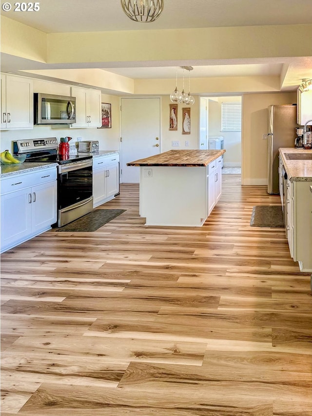130 Terrace Dr, Glide, OR 97443 - kitchen with appliances with stainless steel finishes, butcher block countertops, light wood-style floors, white cabinets, and a center island