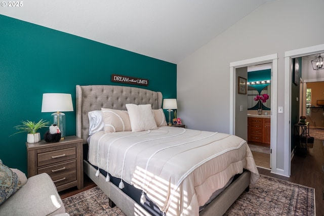 bedroom featuring lofted ceiling, wood finished floors, connected bathroom, and an inviting chandelier