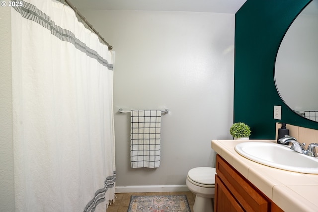 bathroom featuring toilet, baseboards, and vanity