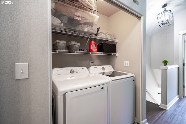 clothes washing area featuring laundry area, washing machine and dryer, wood finished floors, and a textured wall