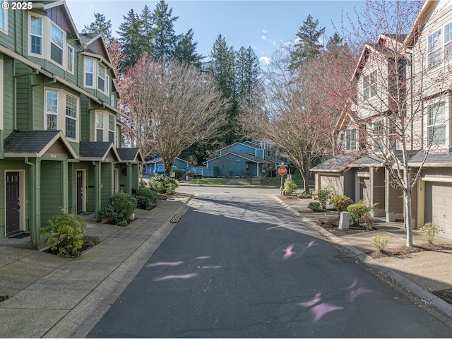 view of road featuring traffic signs, a residential view, and curbs